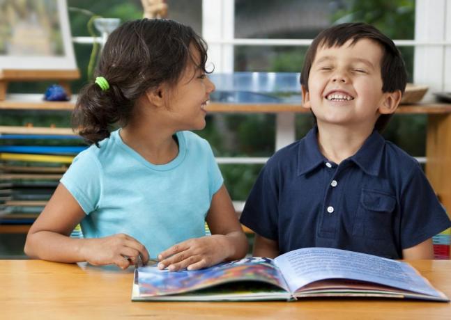 két nevető gyerek élvezi a könyvet az iskolában