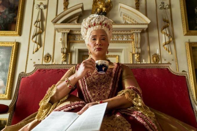 bridgerton golda rosheuvel mint charlotte királynő ül és teázik arany és rózsa ruhában a Bridgerton 105. epizódjában