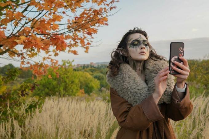 nő halloween elf jelmezben selfie-t vesz az erdőben