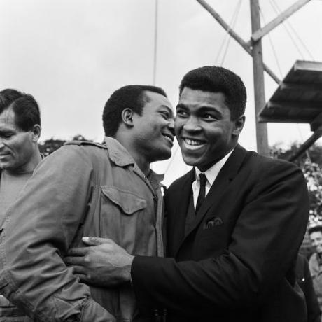 muhammad ali cassius agyag, pihenőt tartott a soron következő brian londoni agyaggal vívott bajnoki küzdelme előtt, látogatást tett a bükkfa park iskolájában játszódó filmben, Markyate, Hertfordshire, ahol mgn a „piszkos tucat” képsorozatait forgatták Muhammad ali köszönti Jim Brownt, 1966. augusztus 6., fotó staffmirrorpixgetty képek