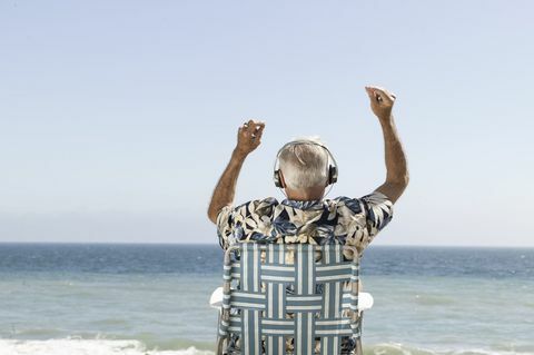 Boldog idős ember hallgat zenét, kilátással a tengerre