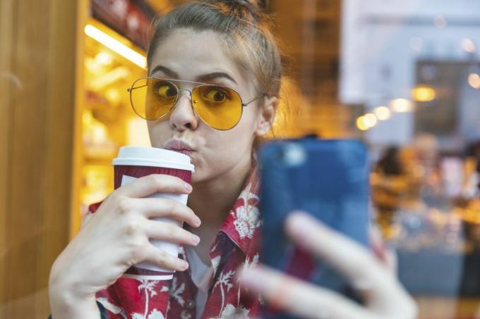 fiatal nő kívül napszemüvegben selfie-t iszik, miközben kávét iszik