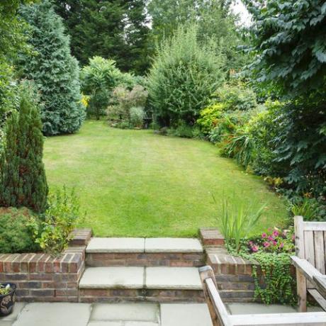 teraszos és parkosított hátsó kert Angliában az Egyesült Királyságban terasszal, füves és kőlépcsőkkel