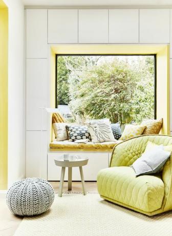 zöld sárga fotel, párnákkal borítva, amelyet ablakpárnával helyeztek el, az ablak bemélyedésének falát festve, ill. az ablakülés nagyszerű módja annak, hogy hangsúlyt helyezzenek a minták eklektikus keverékével összehangolt sémába párnák