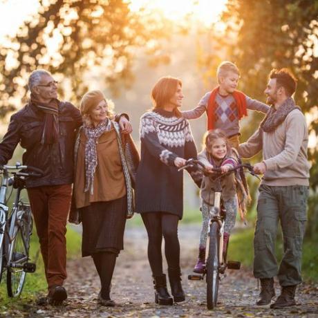 mosolygós többgenerációs család kerékpárral sétál a természetben, és élvezi az együtt töltött időt