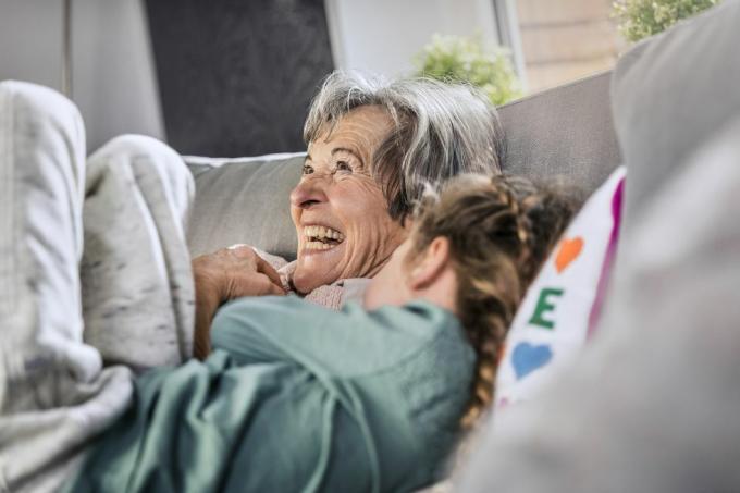 vidám nagymama feküdt az unokája a kanapén otthon