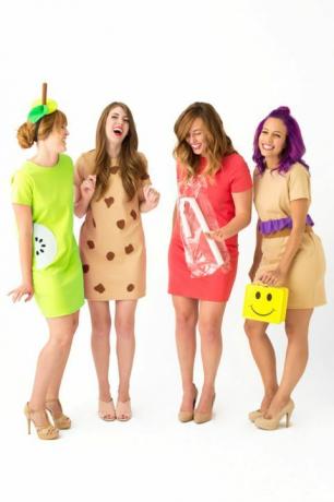 négy nevető, rövid ruhás nő, "ebédhölgynek" öltözve, az egyik sárga mosolygós arcú ebéddobozt visel